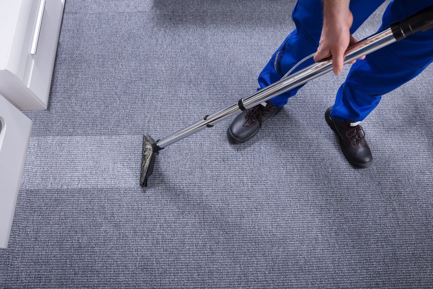 A man in blue pants actively cleans a carpet, highlighting a carpet cleaning service based in San Francisco, CA.