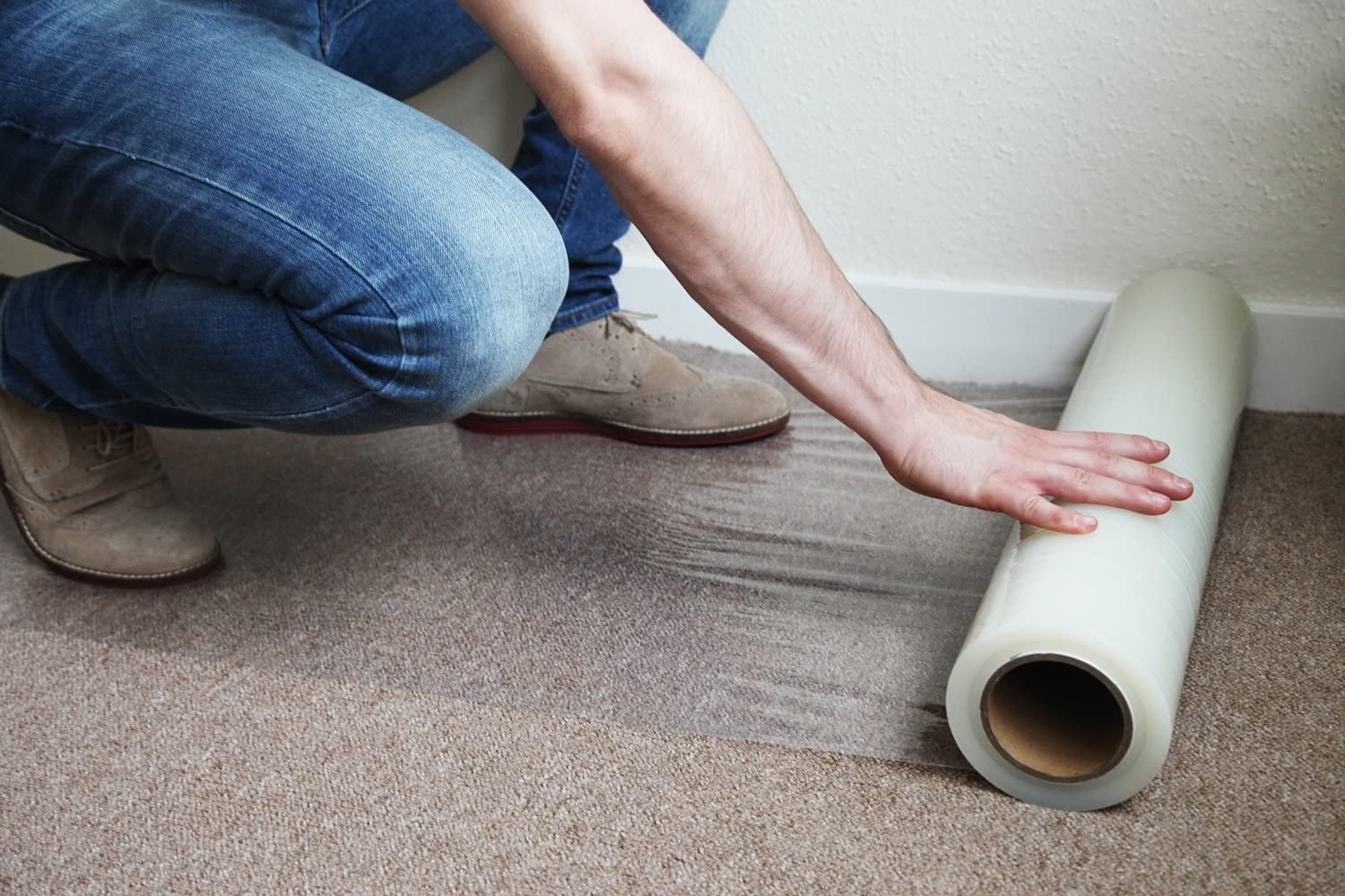 A man positions a roll of plastic on the floor, contributing to a protection service in San Francisco, CA.
