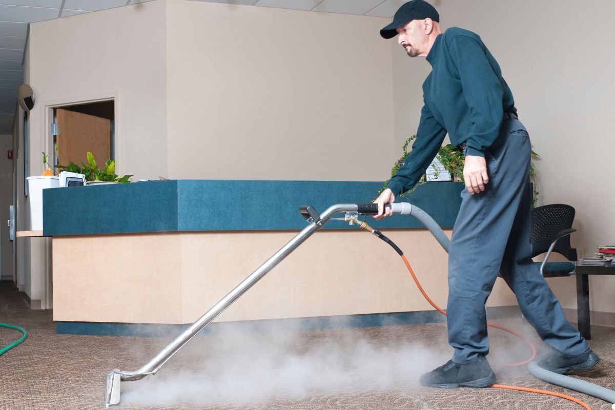 A man operates a vacuum cleaner on a carpet, focusing on removing dirt and debris from the surface.