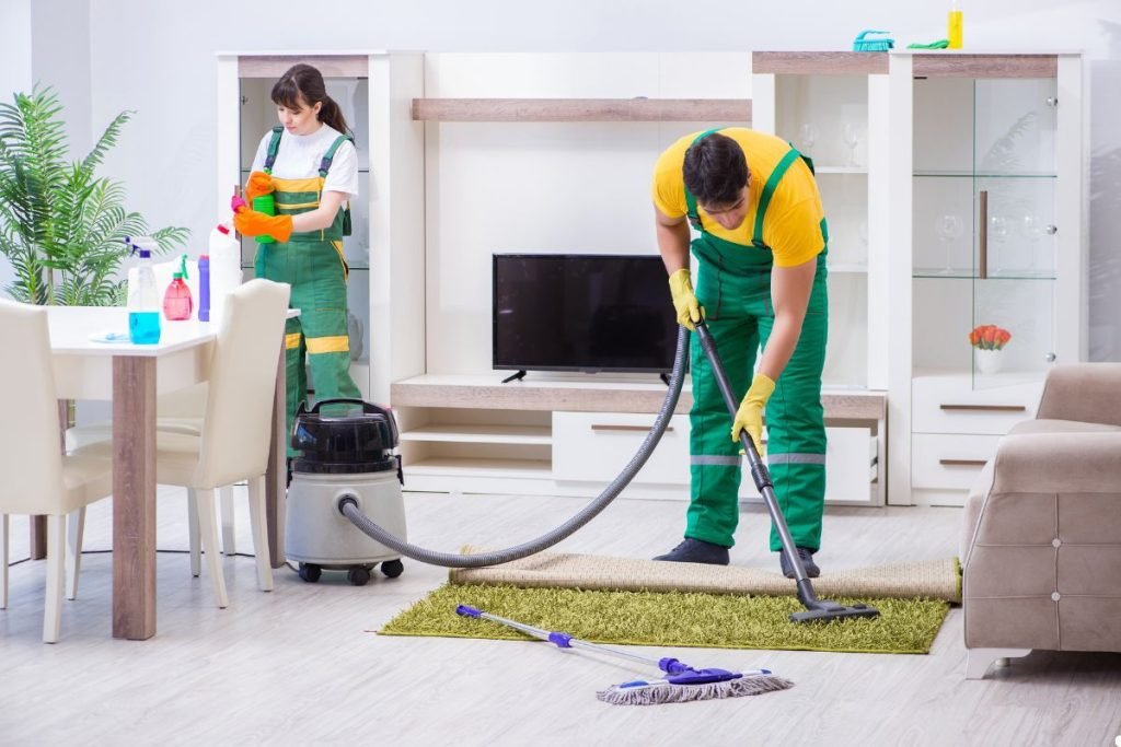 Two individuals vacuuming a room, focused on cleaning the floor and maintaining a tidy environment.