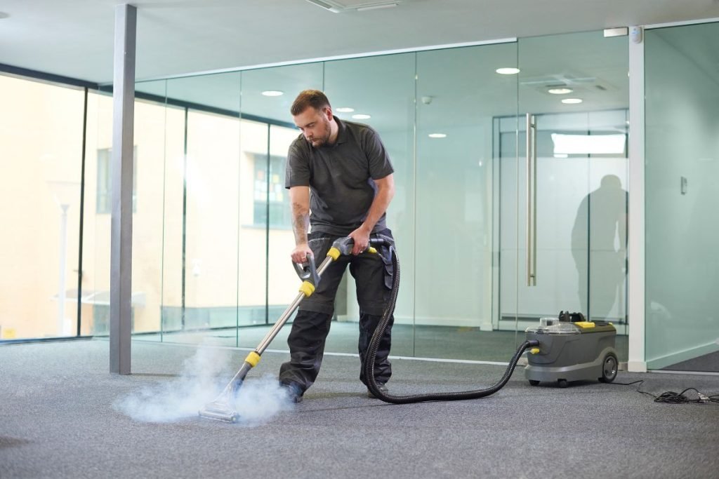 A man using a vacuum cleaner to clean a carpet, demonstrating a method that requires only water for effective cleaning.
